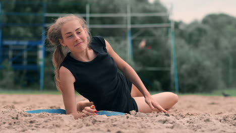 Young-female-athlete-dives-into-the-sand-and-saves-a-point-during-beach-volleyball-match.-Cheerful-Caucasian-girl-jumps-and-crashes-into-the-white-sand-during-a-beach-volley-tournament.